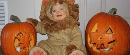 a young child dressed in a tiger costume between two jack-o-lanterns