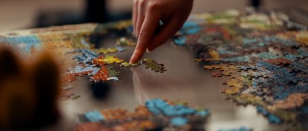 a finger hovers over a partially completed jigsaw puzzle and free puzzles pieces